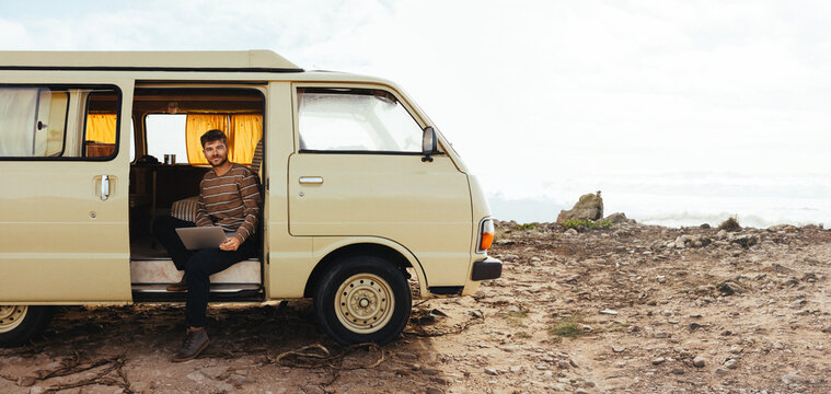 Van life traveler working on laptop at a remote coastal camp