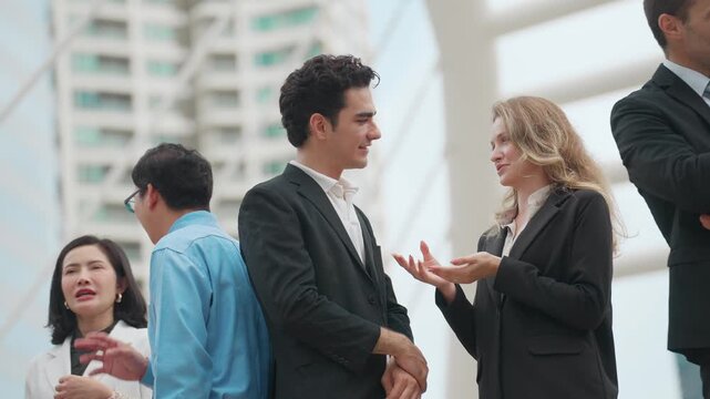 Professional colleagues converse in a modern office space. Man and woman smile while engaging in friendly conversation