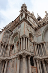 Fototapeta premium Low angle perspective of the ornate gothic marble facade and intricate stone sculptures of Saint Mark Basilica in Venice