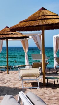 Vertical view of the beach with umbrellas and wooden armchairs overlooking the turquoise Mediterranean Sea in sunny Italy