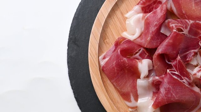 Plate of serrano ham rotating on white background
