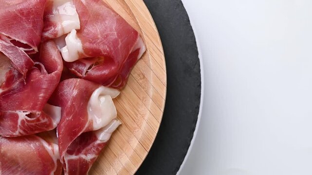 Plate of serrano ham rotating on white background