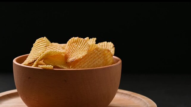 Bowl of potato chips rotating on black background
