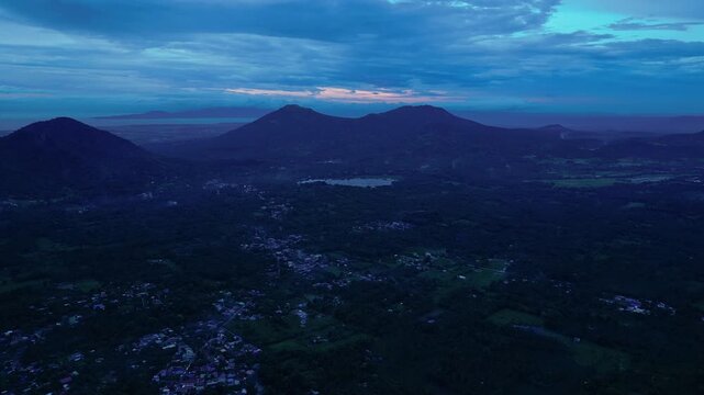 Dawn aerial footage documenting the Sampaloc Lake with Mount San Cristobal rising beyond the skyline of San Pablo City, Laguna, Philippines.