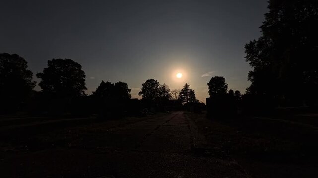 2026 Solar eclipse moving slowly across glowing silhouette trees making stone path darker