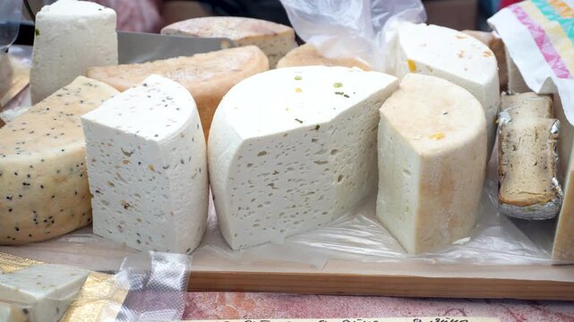 Large pieces of cheese of different types lie on the counter. Sale of cheese in a cheese shop.
