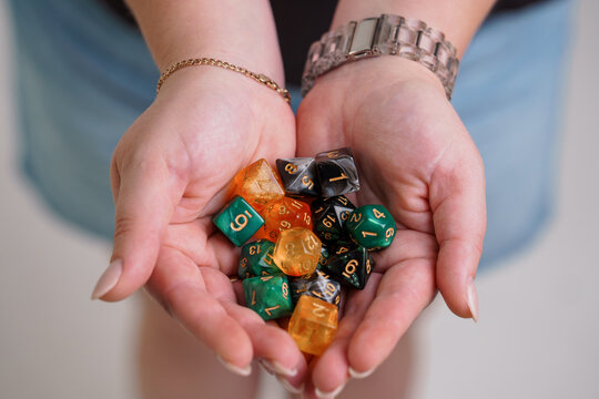 Person Holding Colorful Polyhedral Gaming Dice in Cupped Hands Against a Soft Blurred Background