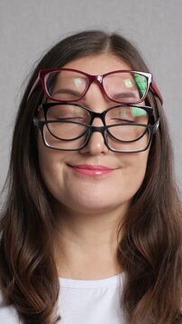 Young woman with poor eyesight wearing two pairs of glasses making funny and silly faces, starting confused and then smiling happily, concept of vision problems and ophthalmology
