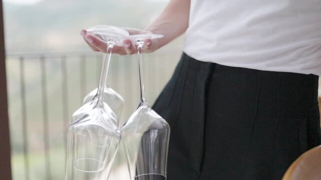 Waitress carefully carrying empty wine glasses