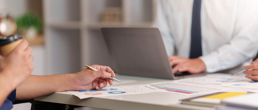 Business team analyzing financial data on laptop and paper reports in office