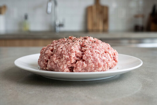 Freshly ground raw pork meat on white plate.