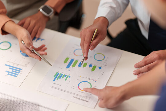 Business team hands pointing at financial charts during data strategy meeting