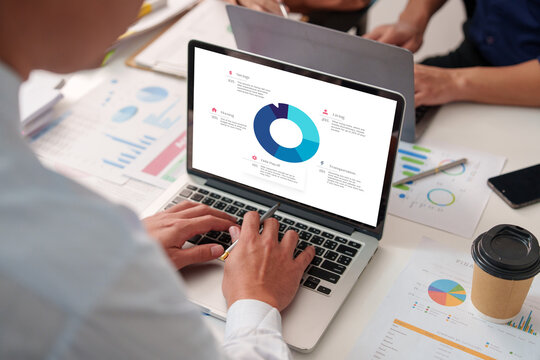 Over the Shoulder View of Person Analyzing Financial Budget Chart on Laptop Desk