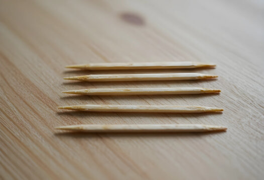 Oral hygiene and dental care, wooden toothpicks for food and teeth cleaning on a light wood background