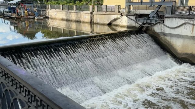 Water flowing over urban dam in city canal creating relaxing background scene