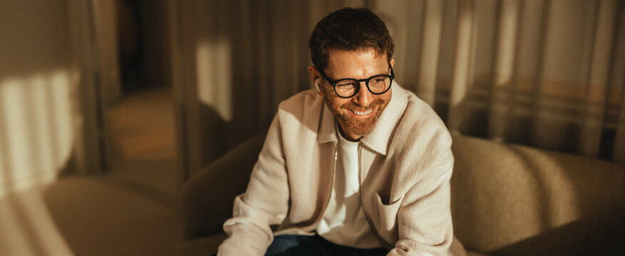 Business man smiles while sitting on a sofa in a relaxed office portrait