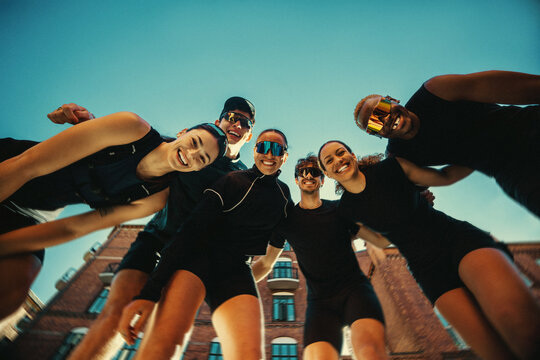 Running group of friends smiling at camera in urban setting
