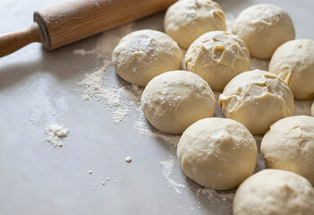 Fototapeta premium Homemade baking and cooking preparation, fresh dough balls with flour and a rolling pin on a kitchen counter