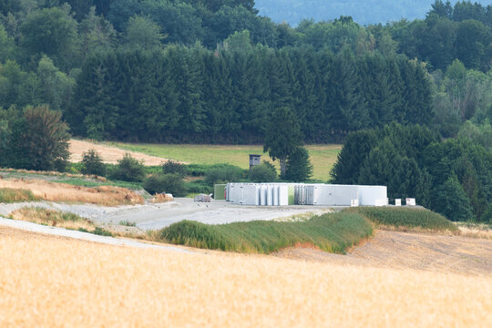 Construction site, preparation for building wind turbine farm, concrete tower section, foundation area, rows of curved segments, gravel ground in forest, Germany