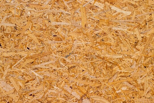  Close up background of oriented strand board panel texture showing compressed wooden strands flakes and chips for construction engineering copy space