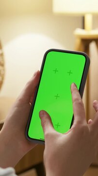Woman use digital tech cell phone zoom in photo on green screen mock up. Hand press click phone web site middle center. Girl hold mobile. Chroma key page. Cozy home background. Online app copy space.