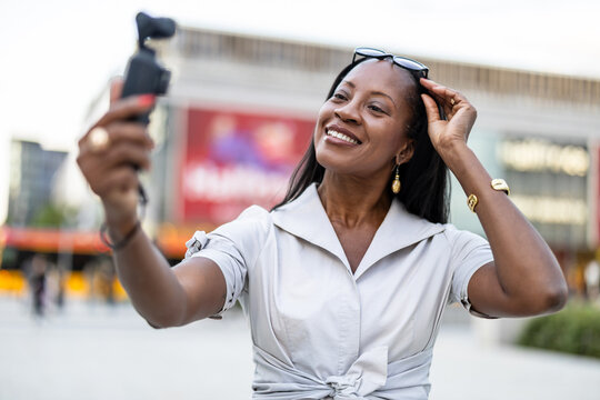 Woman filming a vlog in the city using a pocket-sized camera
