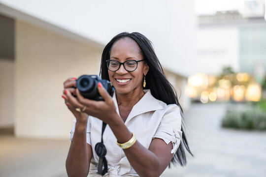 Portrait of happy woman taking photo with camera in the city.
