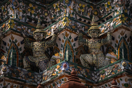 Mythical Yaksha Guardians supporting the ascending tiers of the sacred structure of Wat Arun, Temple of Dawn in Bangkok, Thailand.