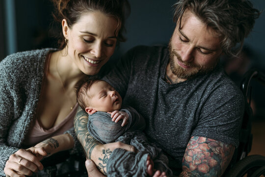 Happy Mother and Father in Wheelchair Holding Newborn Baby