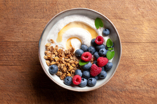 Granola bowl with greek yogurt, berries and honey for healthy breakfast.