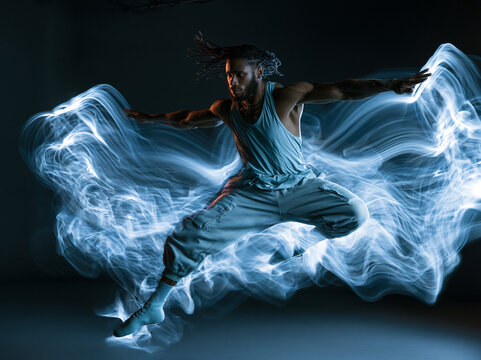 Dynamic Male Dancer Leaping with Glowing Blue Light Trails