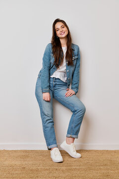 Pretty girl in blue denim jacket and white t-shirt poses happily in a studio