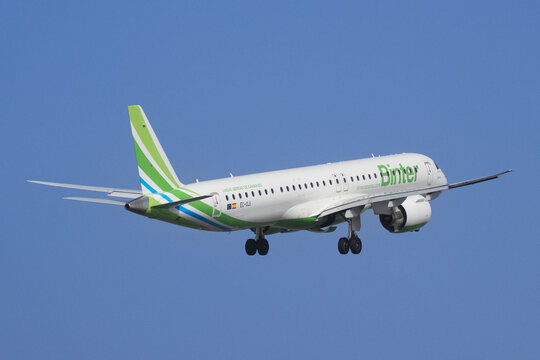Un reactor Embraer E195-E2 de Binter Canarias volando en aproximaci&oacute;n con el tren de aterrizaje desplegado sobre un cielo azul despejado.