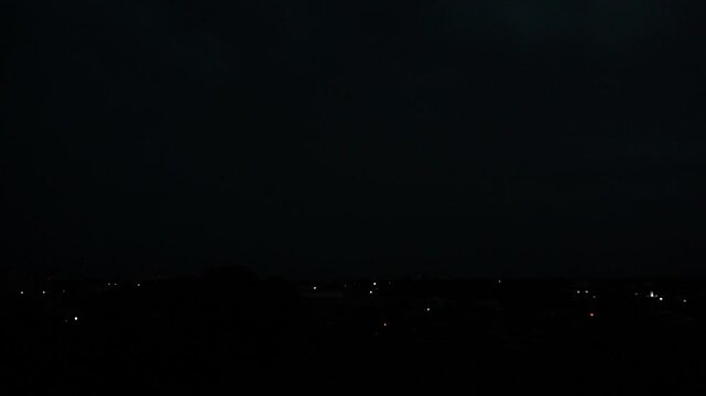 Lightning storm over night city skyline with flashing bolts in dark sky