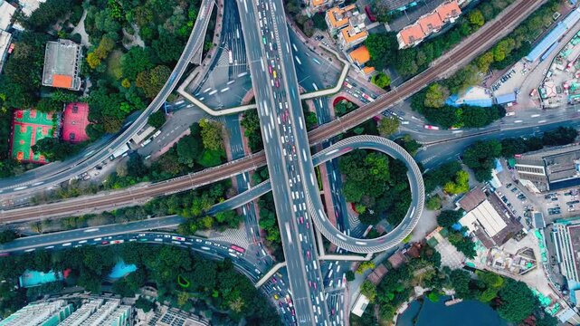 Top down aerial timelapse of curved ramps and multilane roadways at a modern urban highway interchange in China. The footage shows traffic flow, circular road geometry and transportation infrastructur