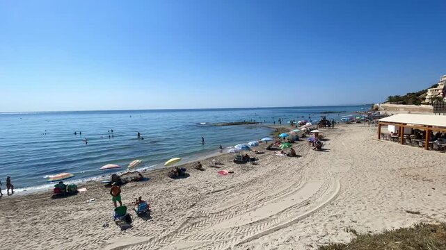 Playa, poner la sombrilla time lapse, chiringuito, ba&ntilde;istas, paseo por la orilla del mar, ola en verano con ba&ntilde;istas tomando el sol, arena, horizonte cielo azul y vacaciones velocidad r&aacute;pida acelerado