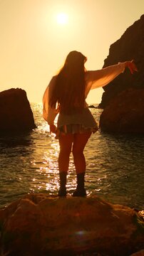 Sunset woman dancing woman dancing on a rock by the sea during a golden sunset silhouette