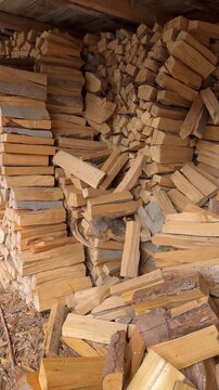 Gestapeltes Brennholz als Heizmaterial f&uuml;r den Winter - Trocken gelagertes und gespaltenes Brennholz unter einem Unterstand. Holz als Brennstoff f&uuml;r Ofen und Kamin sowie zur W&auml;rmeversorgung im Winter.