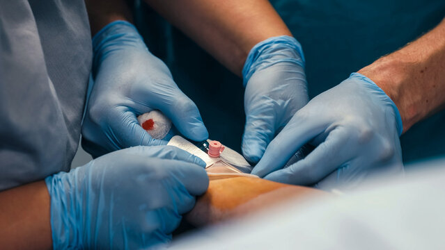 Medical professional in gloves performs intravenous cannula insertion to establish peripheral venous access.
