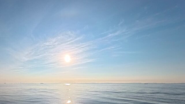 Airy sky background footage featuring pastel blue gradient, light cloud textures, and gentle ocean reflection