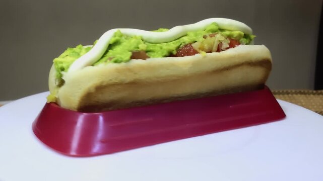 Chilean completo italiano hot dog rotating 360 degrees, traditional Chilean street food with avocado, tomato and mayonnaise, authentic Latin American fast food