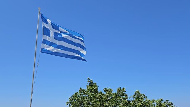 Greek national flag waving in blue sky in Greece