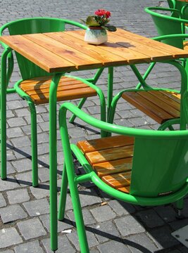 Green metal chairs and wooden table inviting customers in outdoor cafe