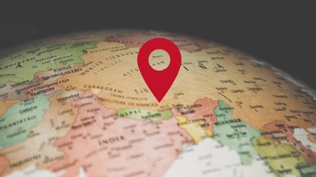 Red location pin drops on spinning globe with detailed world map texture and continents