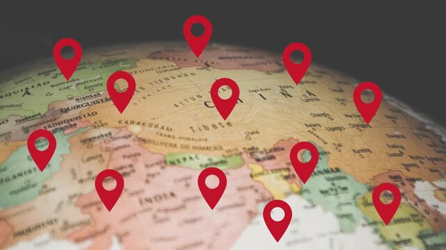 Red location pins dropping onto spinning 3D globe with detailed world map for travel planning