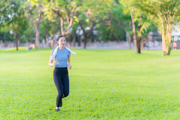 Fototapeta premium Young Asian woman in sportswear jogging and exercising outdoors in the park