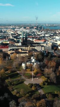 Stunning aerial perspective showing the colorful kaivopuisto park during autumn, with the beautiful helsinki cityscape, saint john's church, and the baltic sea in the background