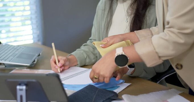 Prompted by review, hands are arranging and stacking swatches at desk for color selection notes