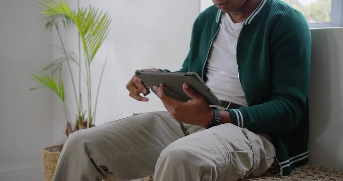 African American man sliding card into tablet folio, tapping screen to view content near window