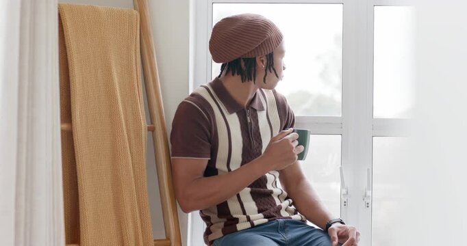 African American man sitting at window with green mug, turning head scanning as light bringing calm